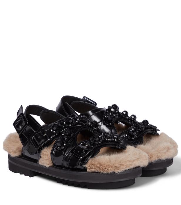 Ein Paar schwarze Sandalen mit Schmucksteinen und Fellbesatz.