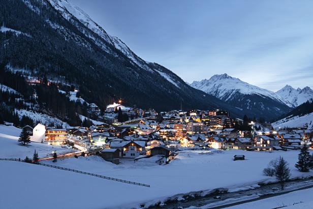 Das verschneite Bergdorf Lech leuchtet in der Abenddämmerung.