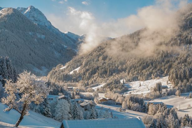 Eine verschneite Landschaft mit Bergen, Bäumen und Häusern im Winter.