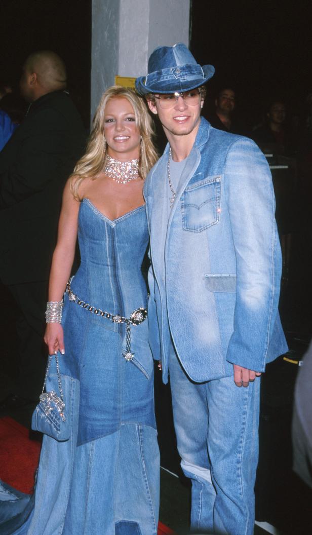 Britney Spears und Justin Timberlake in passenden Jeans-Outfits auf einem roten Teppich.