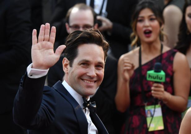 Paul Rudd lächelt und winkt auf dem roten Teppich.