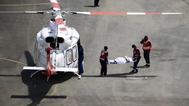 Sanitäter transportieren eine Person auf einer Trage zu einem Rettungshubschrauber.