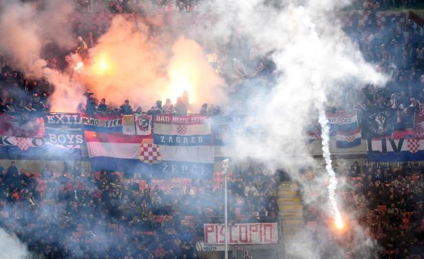 Fußballfans zünden während eines Spiels Rauchbomben und Bengalos.