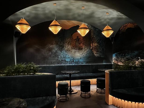 Ein stilvolles Bar-Interieur mit dunklen Möbeln und dekorativer Wandmalerei.