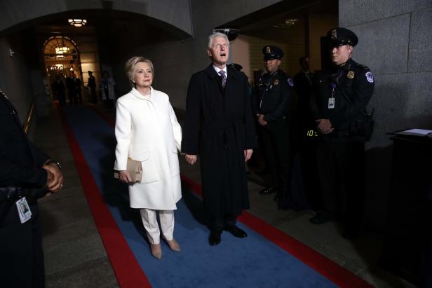 Bill und Hillary Clinton gehen Händchen haltend an Polizisten vorbei.