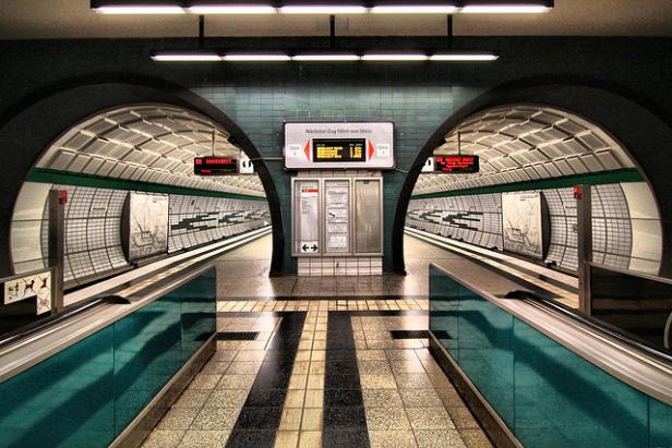 Ein U-Bahnhof mit Bahnsteigen auf beiden Seiten und einer Anzeigetafel in der Mitte.