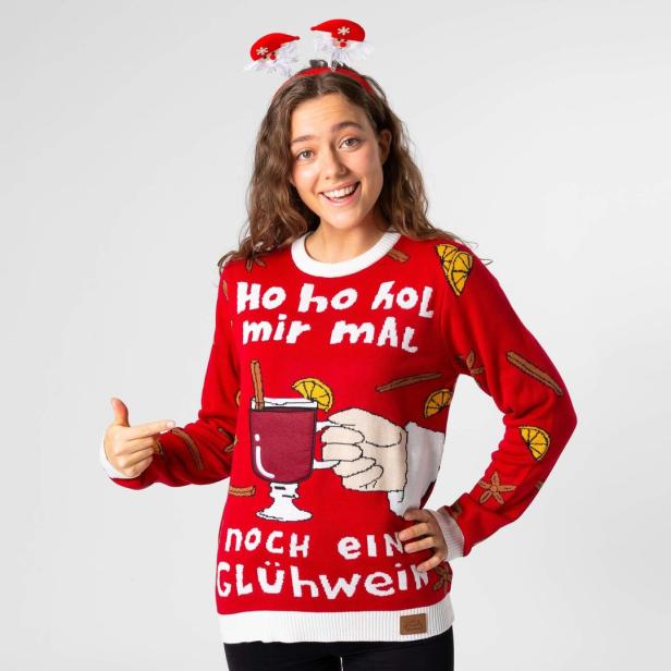 Eine Frau mit Weihnachtsstirnband und einem roten Weihnachtspullover mit Glühweinmotiv.