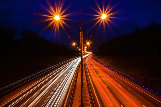Langzeitbelichtung einer Autobahn bei Nacht mit hellen Scheinwerfern.