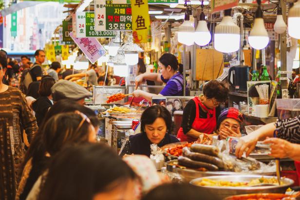Auf einem belebten koreanischen Markt bereiten und verkaufen Händler verschiedene Speisen.