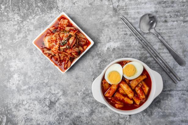 Kimchi und Tteokbokki, koreanische Gerichte, auf einem grauen Tisch.