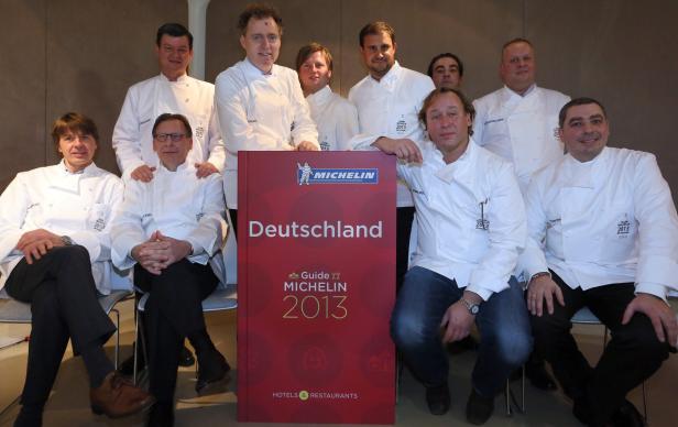 Eine Gruppe von Köchen posiert mit dem Guide Michelin Deutschland 2013.