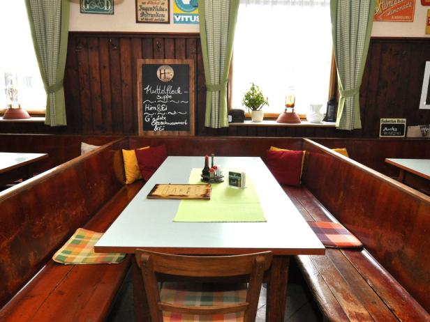Eine traditionelle Gaststube mit Holzbänken und einem gedeckten Tisch.