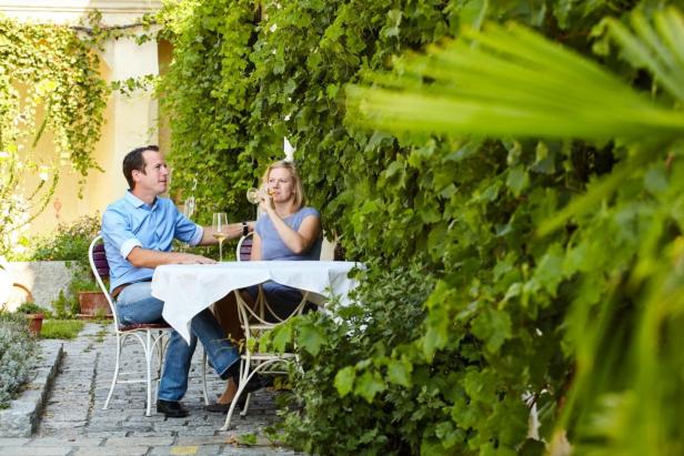 Ein Paar sitzt an einem Tisch im Freien und trinkt Wein.