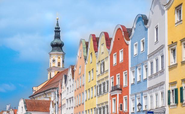 Bunte Häuserfassaden und ein Kirchturm unter blauem Himmel.