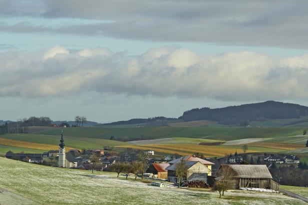 Winterliche Landschaft im Innviertel mit Blick auf ein Dorf und Felder.