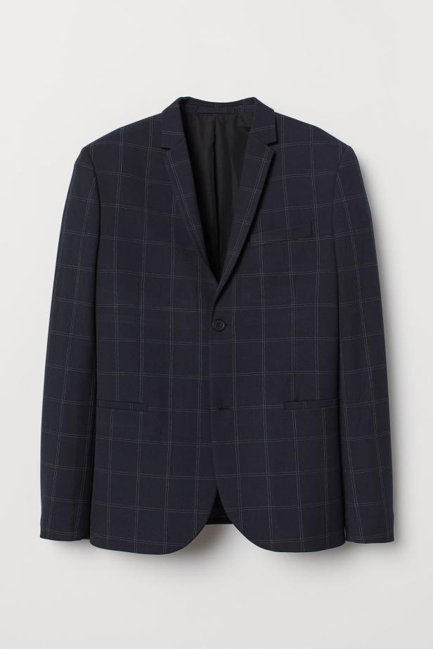 Ein dunkelblauer Blazer mit Karomuster hängt vor einem hellen Hintergrund.