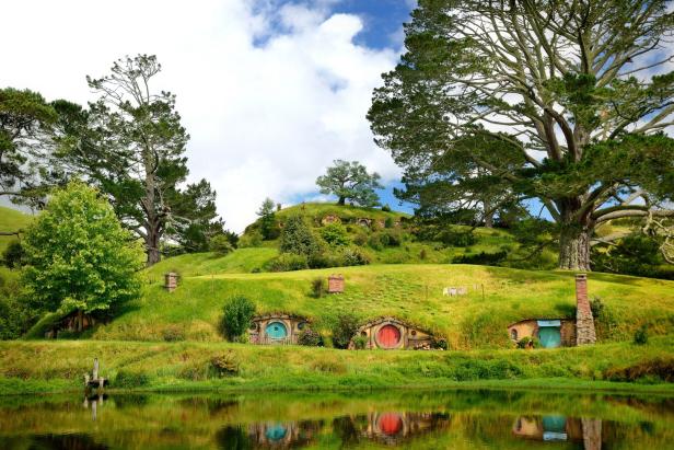 Hügel mit Hobbit-Häusern mit runden Türen, gesehen von einem See aus.