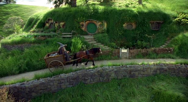 Gandalf fährt mit einem von einem Pferd gezogenen Karren durch Hobbiton.