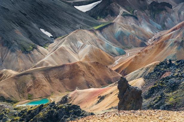 Blick auf eine isländische Berglandschaft mit einem kleinen türkisfarbenen See.