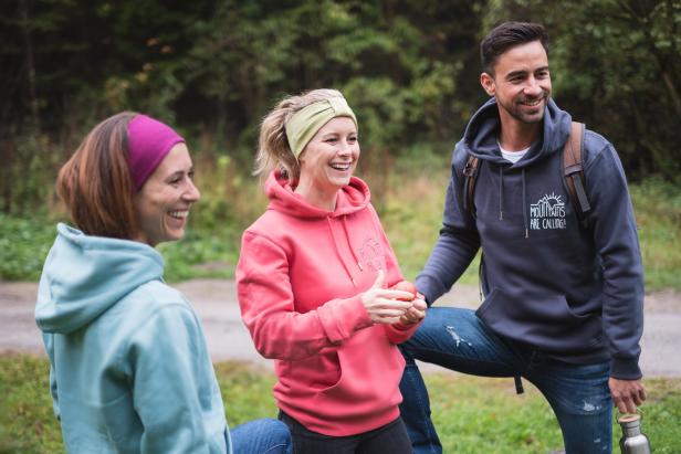 Drei Freunde lachen zusammen im Wald.