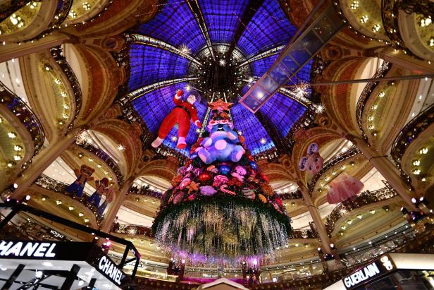 Ein Weihnachtsbaum mit Dekorationen und einem großen blauen Teddybär in einem Kaufhaus.