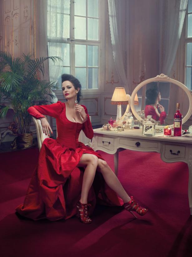 Eva Green sitzt in einem roten Kleid an einem Schminktisch mit Gin und Campari.