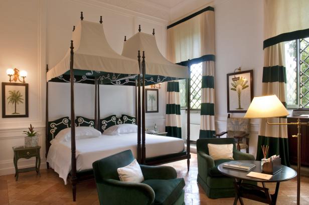 Ein elegantes Schlafzimmer mit Himmelbett, grünen Akzenten und passenden Sesseln.