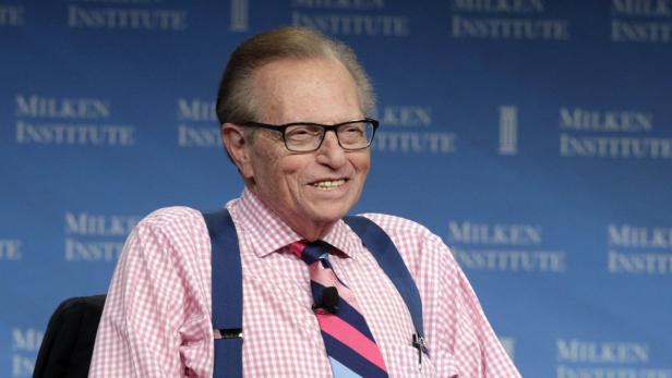 Larry King lächelt vor einem Hintergrund des Milken Institute.