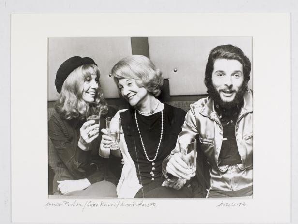 Ein Schwarzweißfoto von Sonja Puhan, Gsta Kellow und André Heller, die mit Gläsern anstoßen.