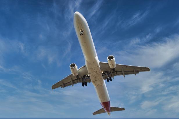 Ein Flugzeug fliegt vor einem blauem Himmel.