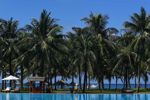 Ein tropischer Urlaubsort mit Palmen, einem Pool und Blick auf das Meer.