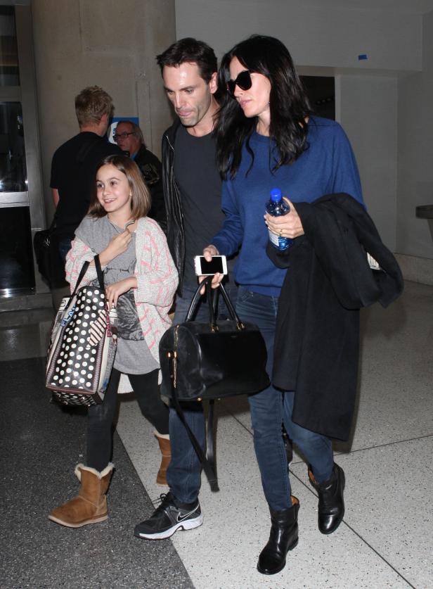 Courteney Cox mit Familie unterwegs, sie trägt eine Wasserflasche und ihr Handy.