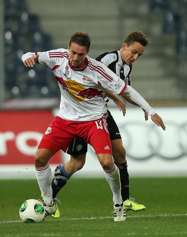 Zwei Fußballspieler kämpfen um den Ball auf dem Spielfeld.