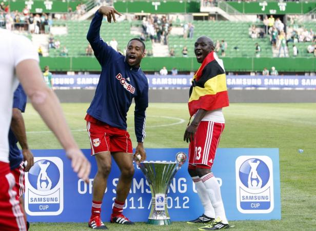 Zwei Fußballspieler feiern mit der Samsung Cup Trophäe auf dem Rasen.