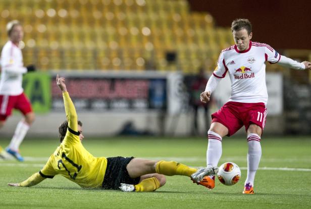 Ein Fußballspieler in Weiß versucht, den Ball an einem am Boden liegenden Spieler vorbeizuspielen.