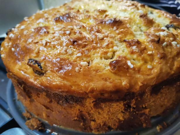 Ein runder Kuchen mit Zuckerguss und Rosinen steht auf einem Teller.