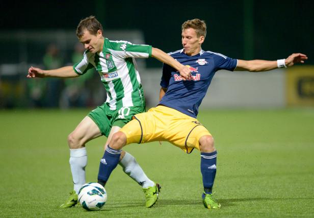 Zwei Fußballspieler kämpfen um den Ball auf dem Spielfeld.