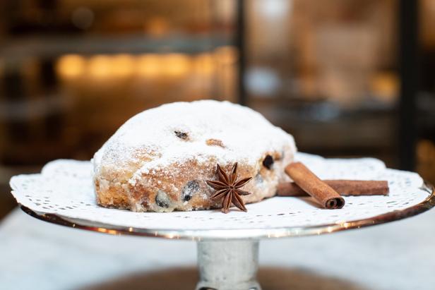 Ein Stollen mit Puderzucker, Sternanis und Zimtstangen auf einem Teller.