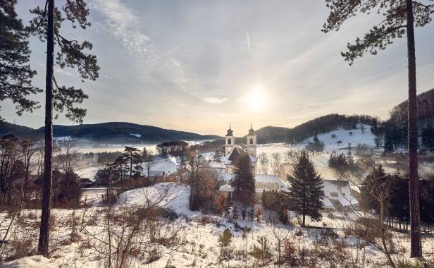 Winterliche Landschaft mit einer Kirche und schneebedeckten Feldern im Morgenlicht.
