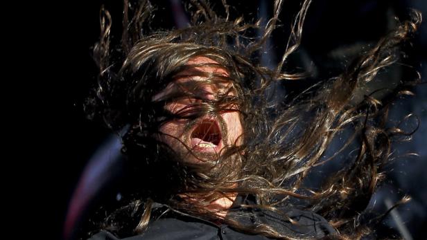 Ein Mann mit langen Haaren schreit und schüttelt den Kopf.