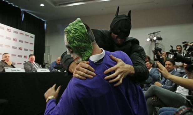 Batman umarmt den Joker vor einer Gruppe von Reportern.