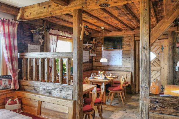 Innenansicht eines gemütlichen Restaurants mit Holzbalken und Tischen mit rotem Dekor.