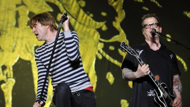 Zwei Musiker treten auf einer Bühne vor einem gelben Hintergrund auf.