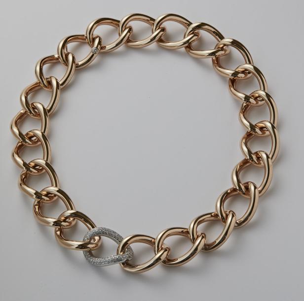 Nahaufnahme einer goldenen Gliederkette mit einem mit Diamanten besetzten Verschluss.