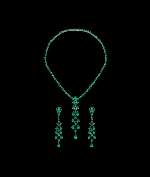 Ein smaragdgrünes Collier und passende Ohrringe auf schwarzem Hintergrund.