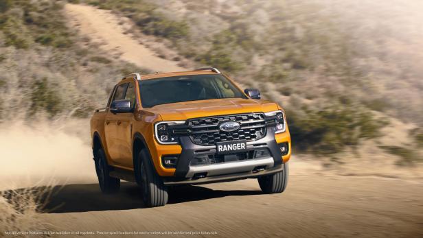 Ein orangefarbener Ford Ranger fährt auf einer unbefestigten Straße.