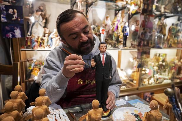 Ein Mann bemalt eine Figur von vermutlich Mario Draghi in seiner Werkstatt.