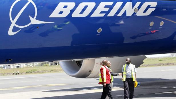 Zwei Flughafenmitarbeiter stehen unter einem Flugzeug von Boeing.