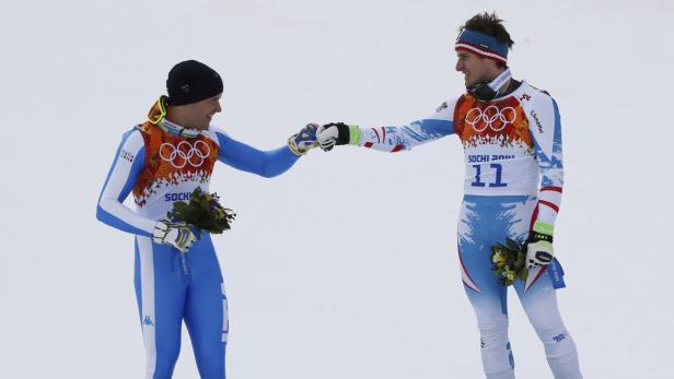 Zwei Skirennläufer in Teamkleidung geben sich ein Faustgruß.