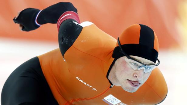 Ein Eisschnellläufer in oranger Wettkampfkleidung auf dem Eis.